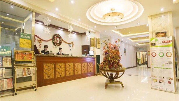 Zona de recepción de un hotel, con mostrador de recepción, un árbol de Navidad y un tablón de anuncios con información.