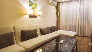 Una habitaci ón de hotel con sofá, una mesita y una ventana con cortinas.