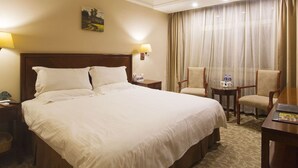 Habitación de hotel con una cama grande, dos sillas, un escritorio y una ventana con cortinas.