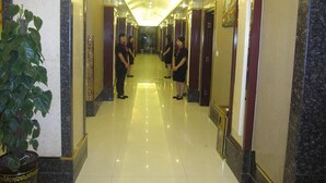 Un pasillo de hotel con suelo de mármol, varias puertas y una planta en maceta.