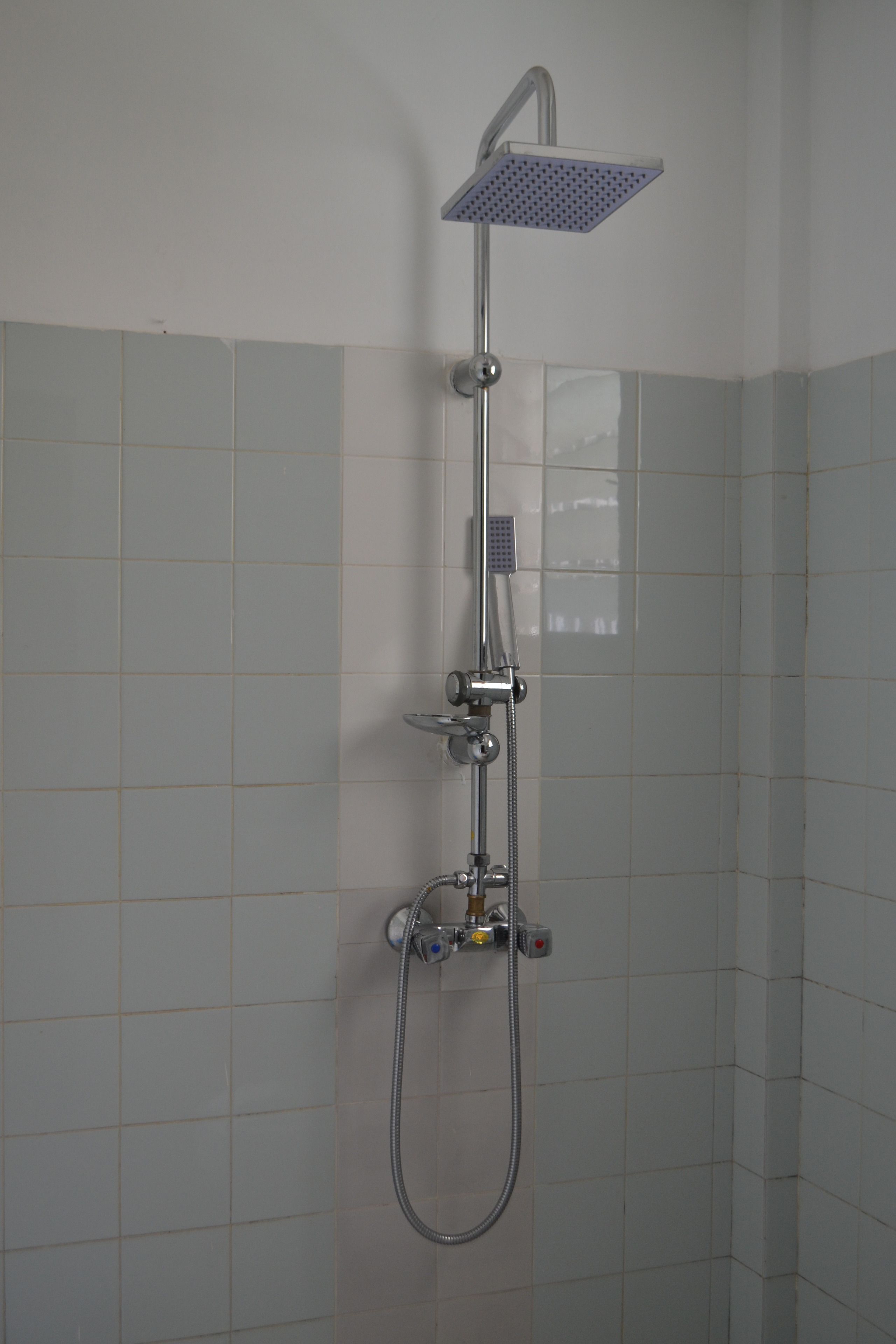 A shower with a square head, a handheld showerhead, and a handheld hose.