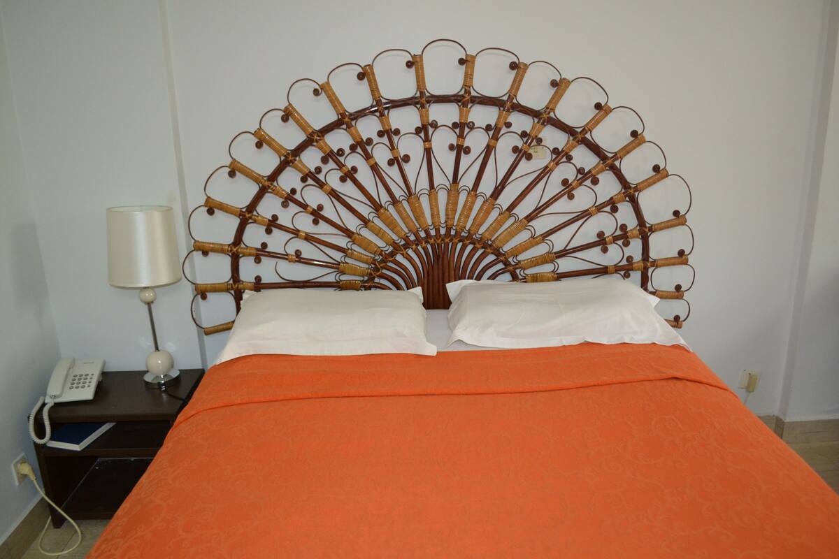 A bed with an ornate metal headboard, a bedside lamp, and a telephone on a nightstand.