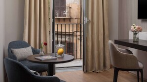 A room with a round table, two chairs, a vase with flowers, a book, and a glass container with a lemon. - NH Collection Palermo Palazzo Sitano (Palermo)