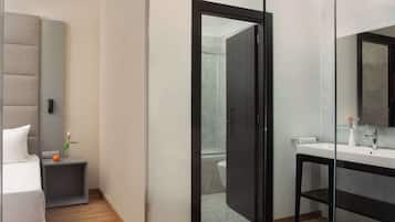 A modern bathroom with a large mirror, a sink, and a shower area.