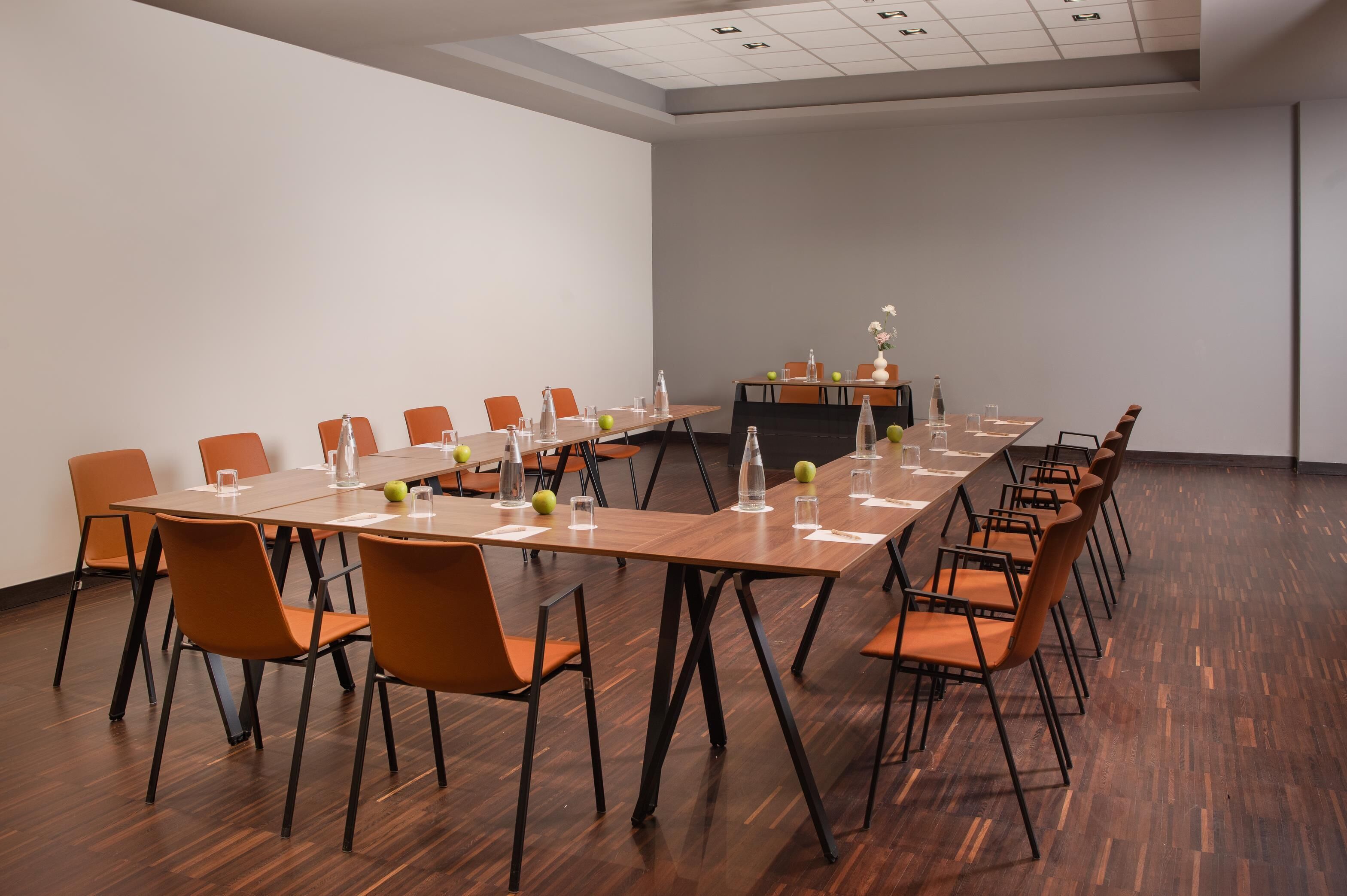 A conference room with a long table, orange chairs, and a whiteboard.