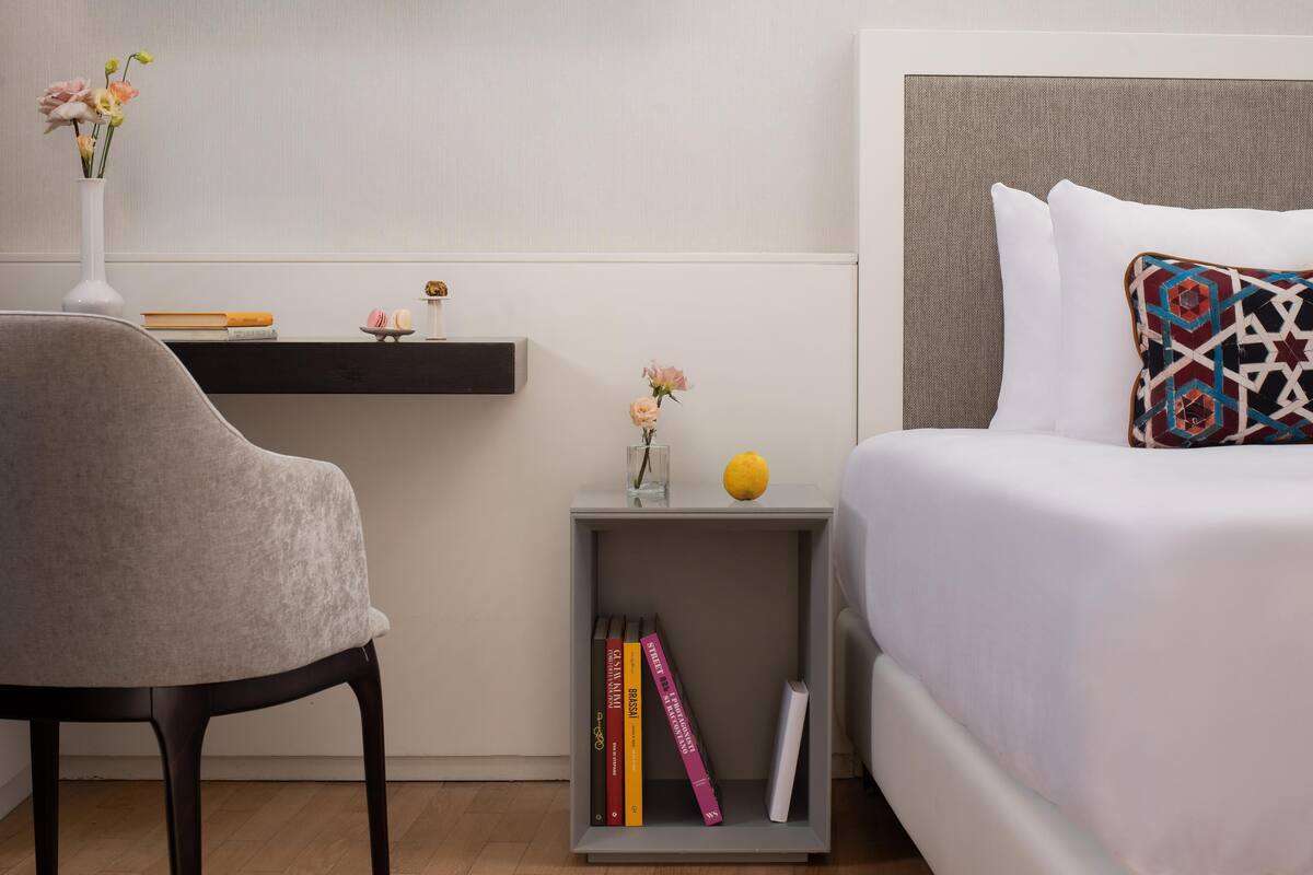 A neatly arranged bedroom with a bed, bedside table, and a chair.