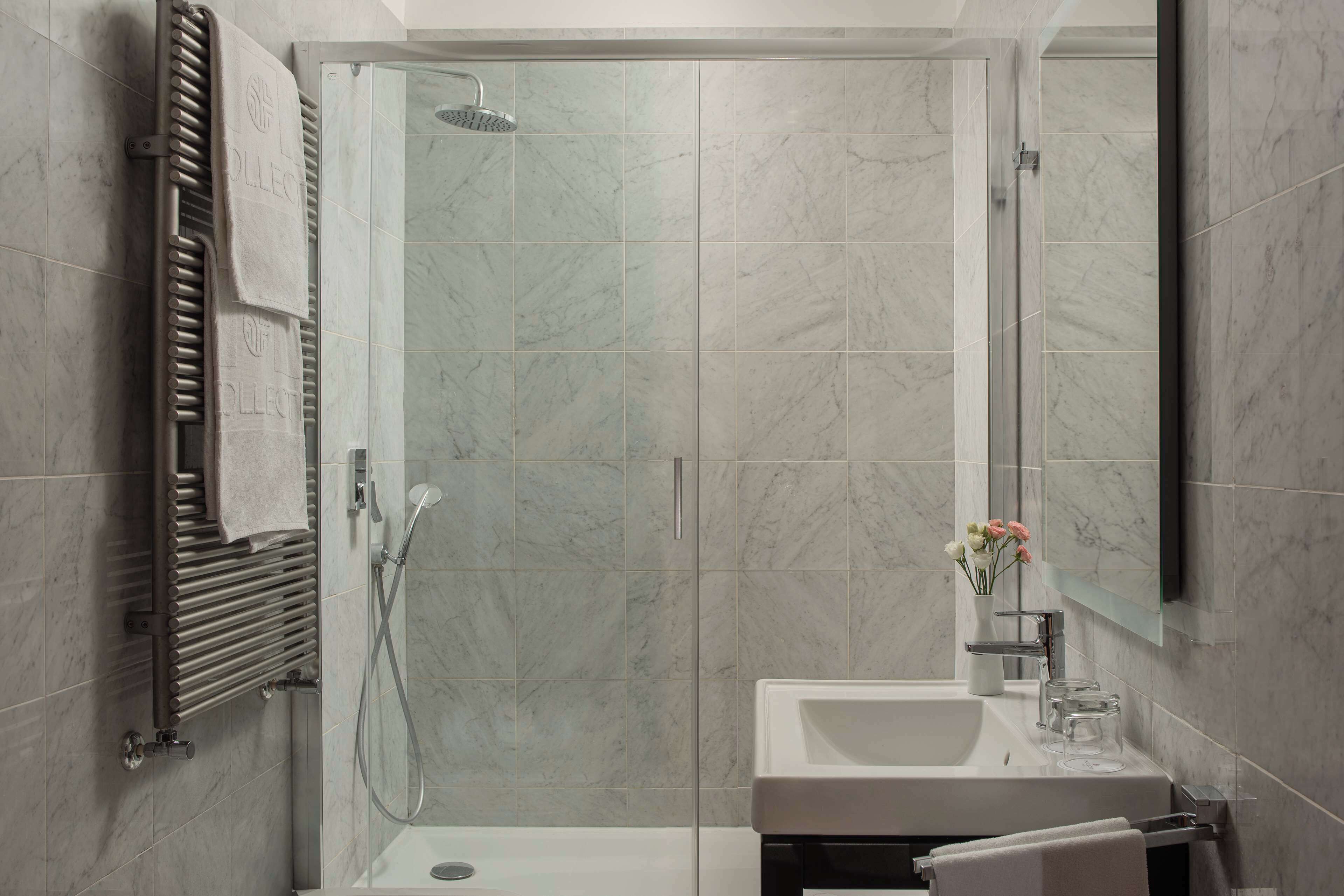 Un bagno moderno con cabina doccia in vetro, lavandino incassato e porta asciugamani.