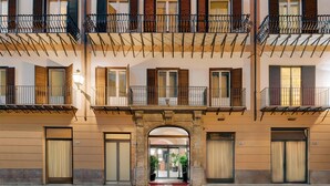 Un edificio de varios pisos con balcones, un arco central y puertas numeradas 110, 112, 114 y 116.