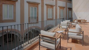 A terrace with outdoor seating, a railing, and a view of the building's architecture. - NH Collection Palermo Palazzo Sitano (Palermo)