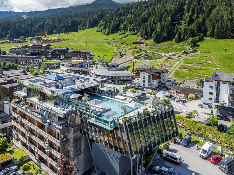Ein modernes Hotel mit Glasatrium, Pool im Freien und Bergblick.