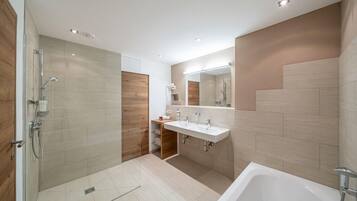 Un baño moderno con cabina de ducha, bañera y tocador doble.