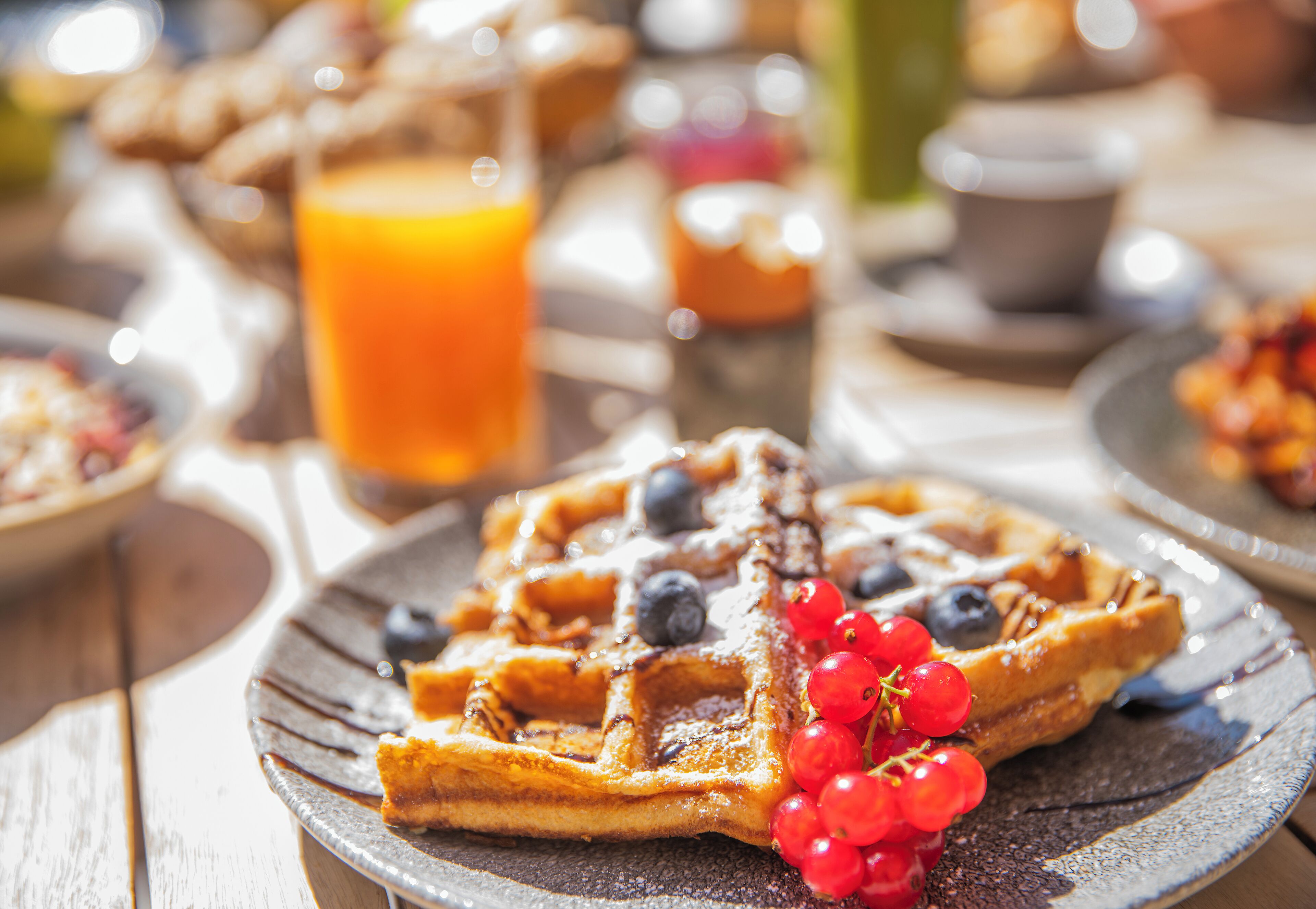 Desayuno con waffles, bayas y un vaso de zumo de naranja.