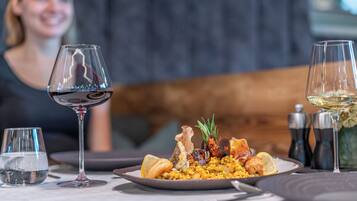 A dining table with a plate of seafood and rice, two wine glasses, and salt and pepper shakers.