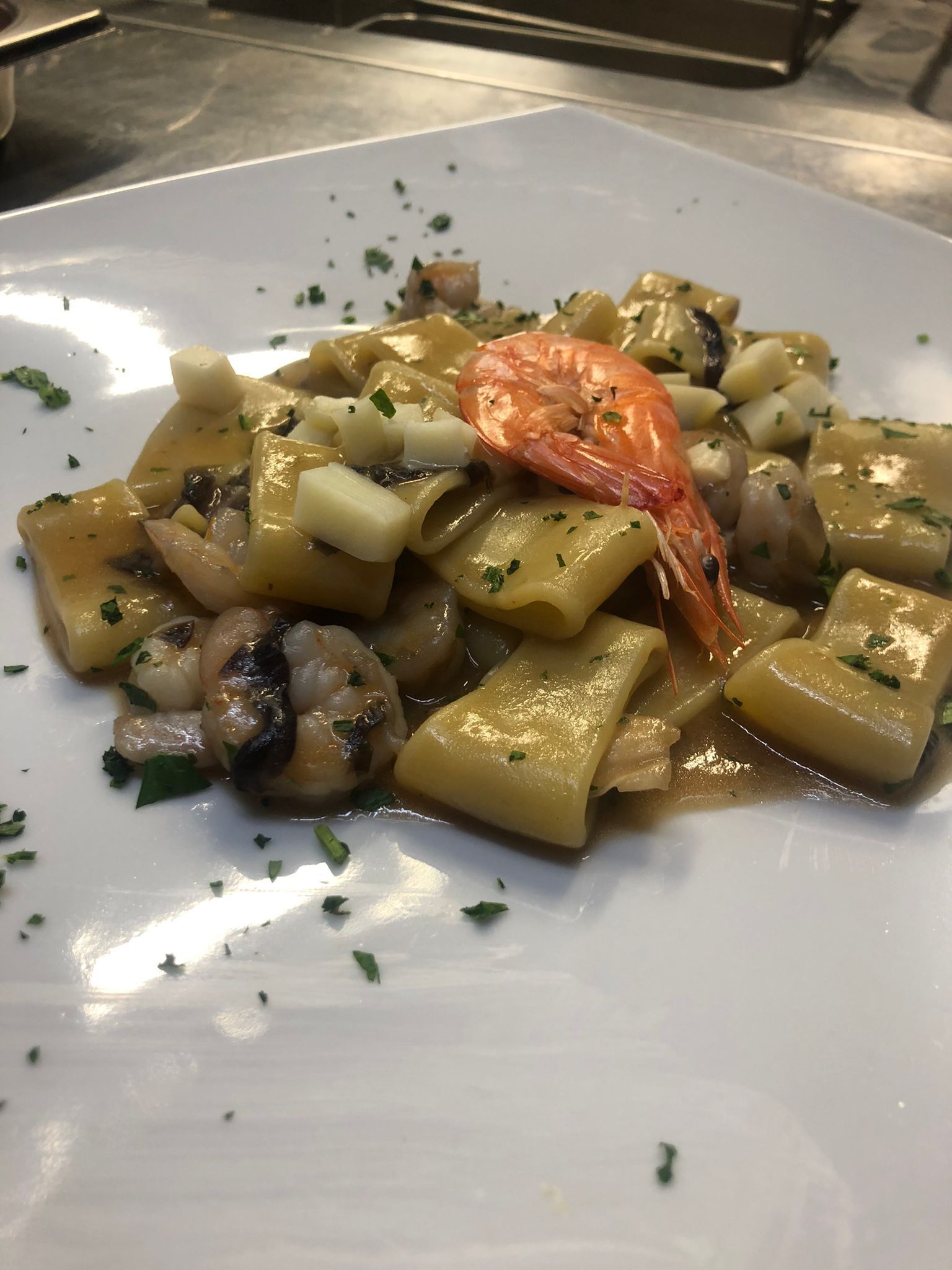 En tallrik pasta med räkor och svamp, garnerad med örter.