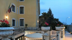 A courtyard with a white railing, potted plants, and a building with multiple windows. - Hotel Euro (San Giovanni Rotondo)