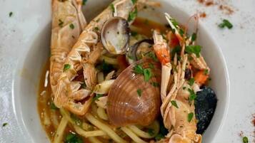 Un plato de mariscos con pasta, almejas y camarones sobre un plato blanco.