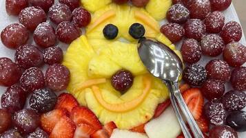 A fruit platter arranged in a smiley face pattern with grapes, strawberries, pineapple, and other fruits.