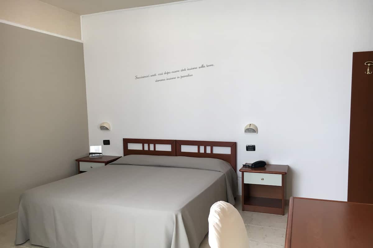 Une chambre d’hôtel avec un lit, des tables de chevet, un bureau et une chaise.