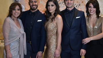 A group of people posing in front of a backdrop with floral and text elements.