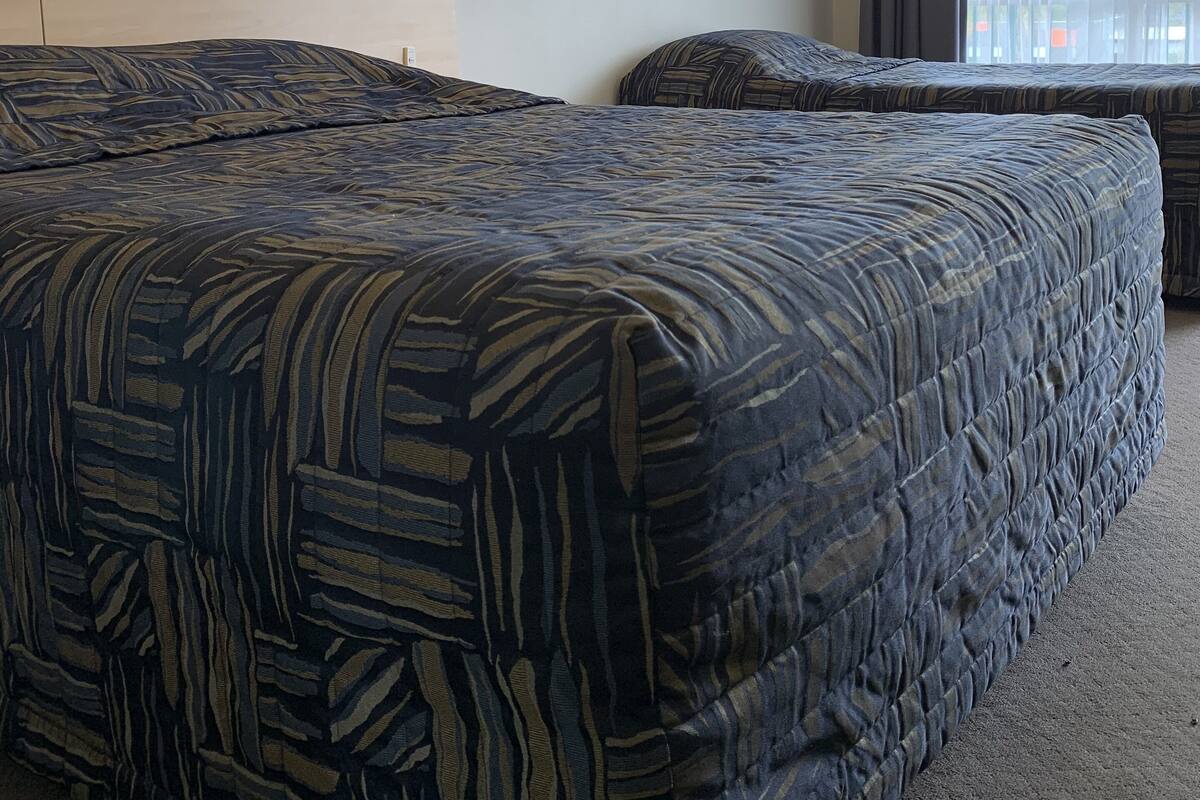 Ein Hotelzimmer mit zwei Betten, einem Kopfteil und zwei Wandleuchten.