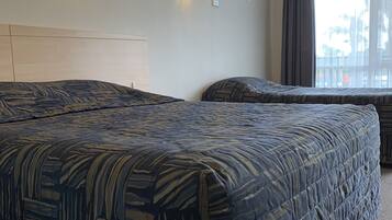 A hotel room with two beds, a headboard, and two wall-mounted lights.