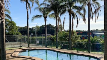 Una piscina al aire libre, sillones reclinables de piscina