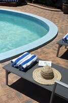 Una piscina al aire libre, sombrillas, sillones reclinables de piscina