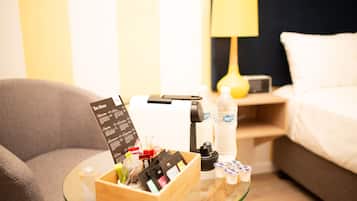 Une chambre d’hôtel avec une table en verre sur laquelle se trouvent un menu de thés, une machine à café et une bouteille d’eau.