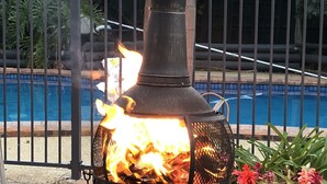 A wood-burning stove with a chimney, positioned in front of a pool. - Tamworth Central Motel (South Tamworth)