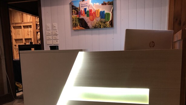 A reception desk with a modern design, a tiled floor, and a wall-mounted sign above it. - Tamworth Central Motel (South Tamworth)