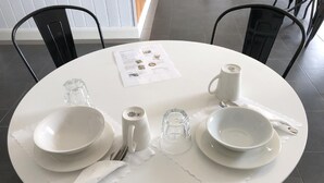 A round dining table set with white plates, bowls, a coffee cup, and cutlery. A menu is placed on the table. - Tamworth Central Motel (South Tamworth)