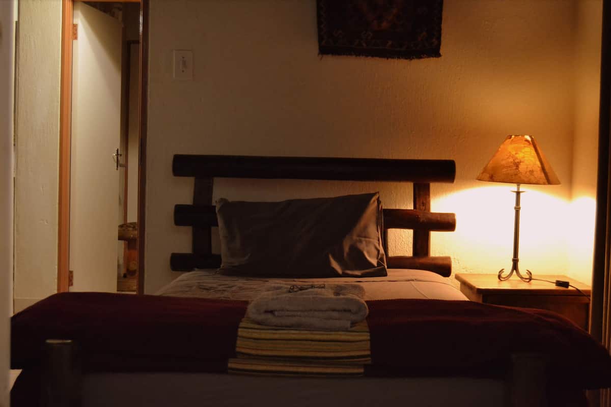 Ein Hotelzimmer mit einem Bett, einem Nachttisch mit Lampe und einer Tür.