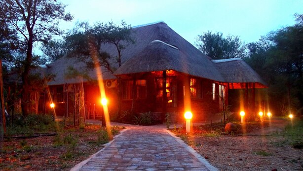 A thatched-roof building with a paved pathway leading to it. - Phumula Kruger Lodge (Nkomazi)