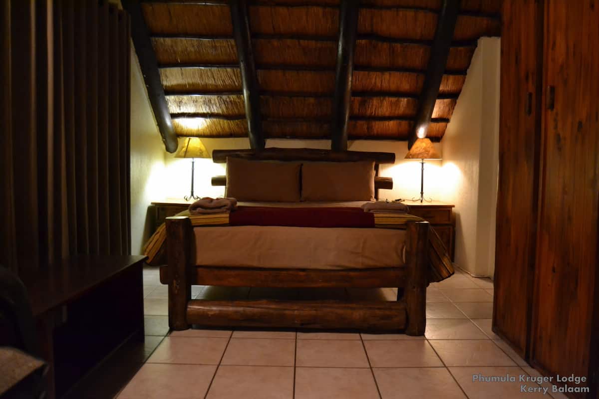 Ein gemütliches Schlafzimmer mit einem hölzernen Bett, zwei Nachttischlampen und einer schrägen Decke.