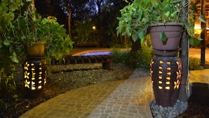 Two illuminated planters with plants on a paved pathway. - Phumula Kruger Lodge (Nkomazi)