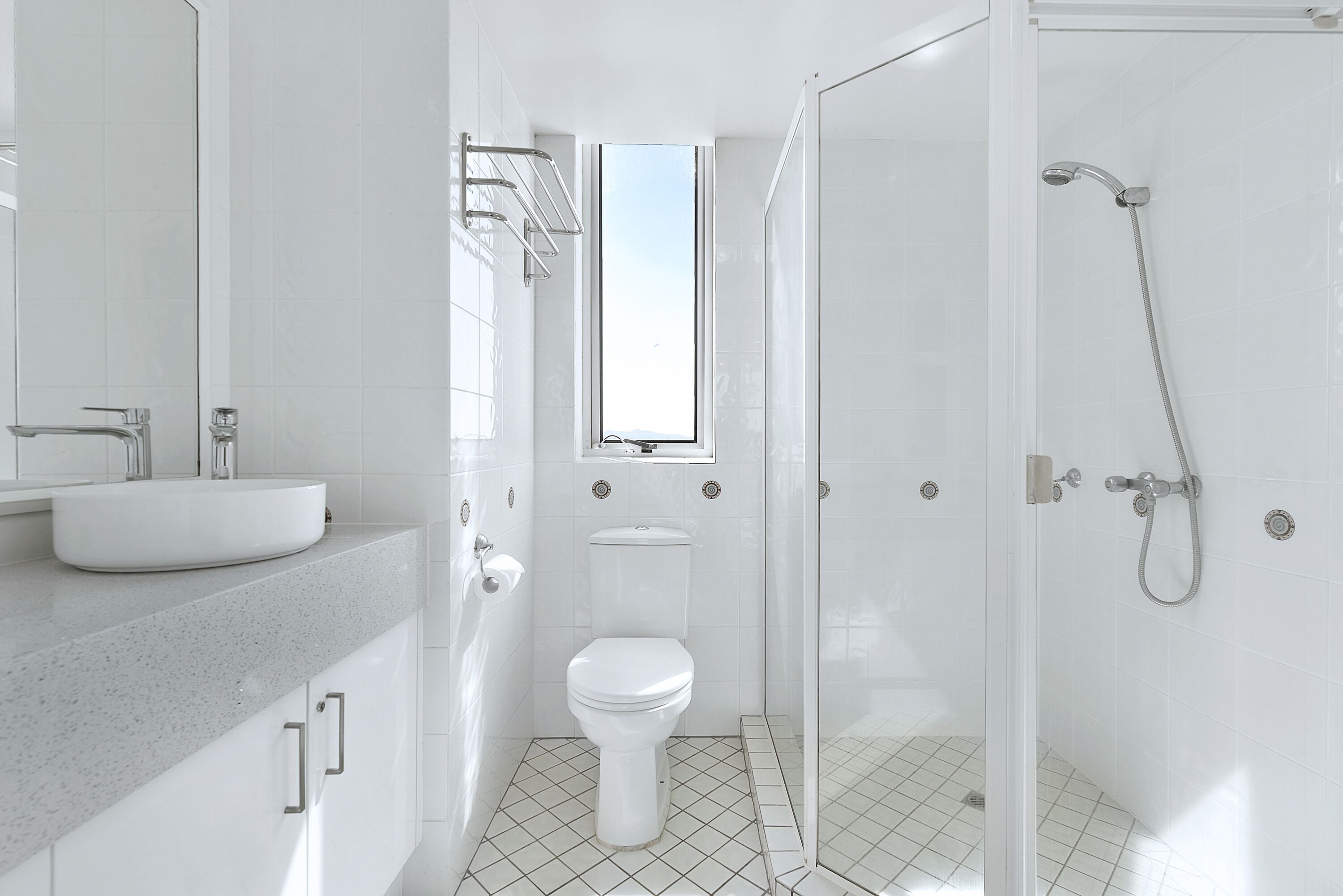 A modern bathroom with a white sink, toilet, and shower.