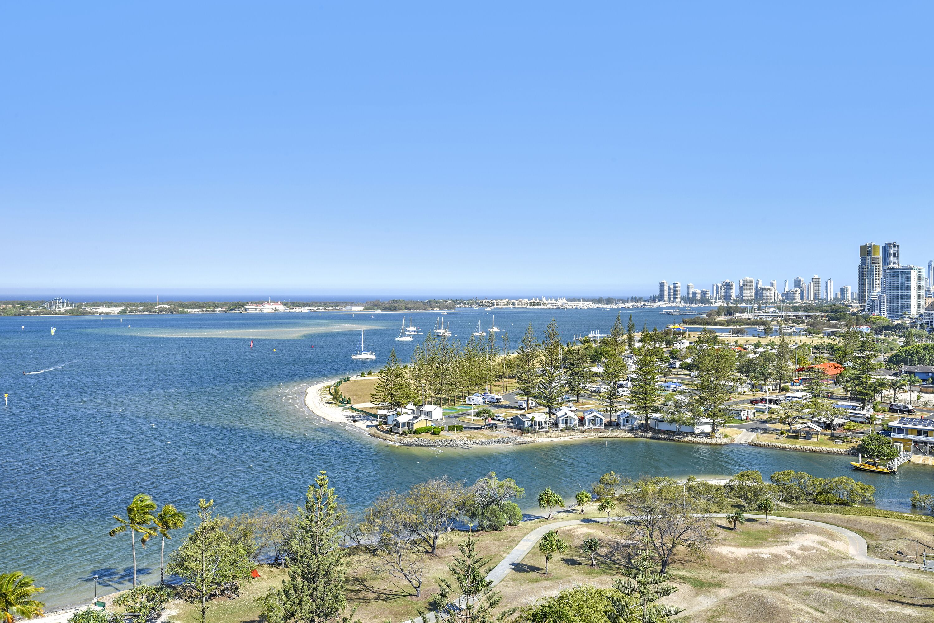A coastal area with a marina, beach, and a city skyline in the background.