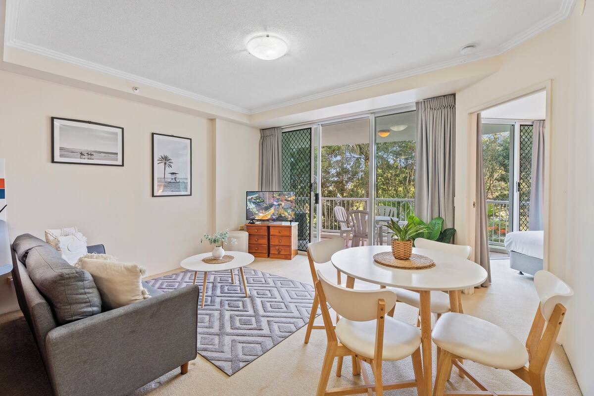 A modern living room with a sofa, dining table, chairs, and a TV.