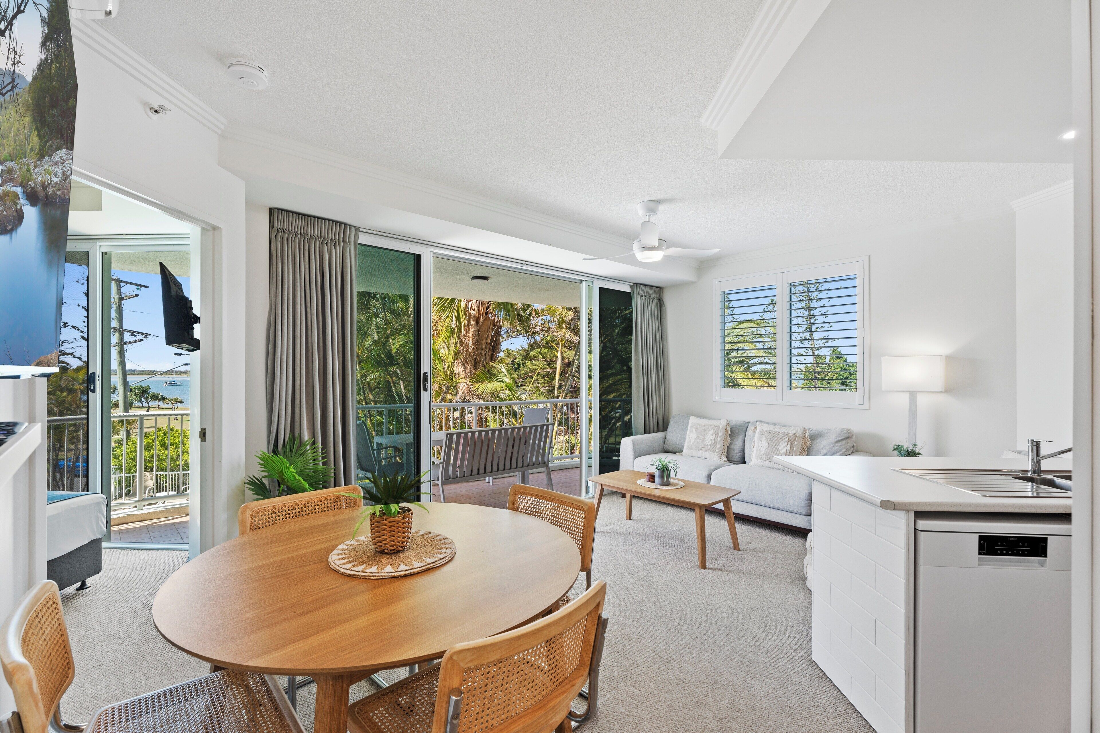 A modern living room with a dining area, a kitchen, and a balcony with a view.