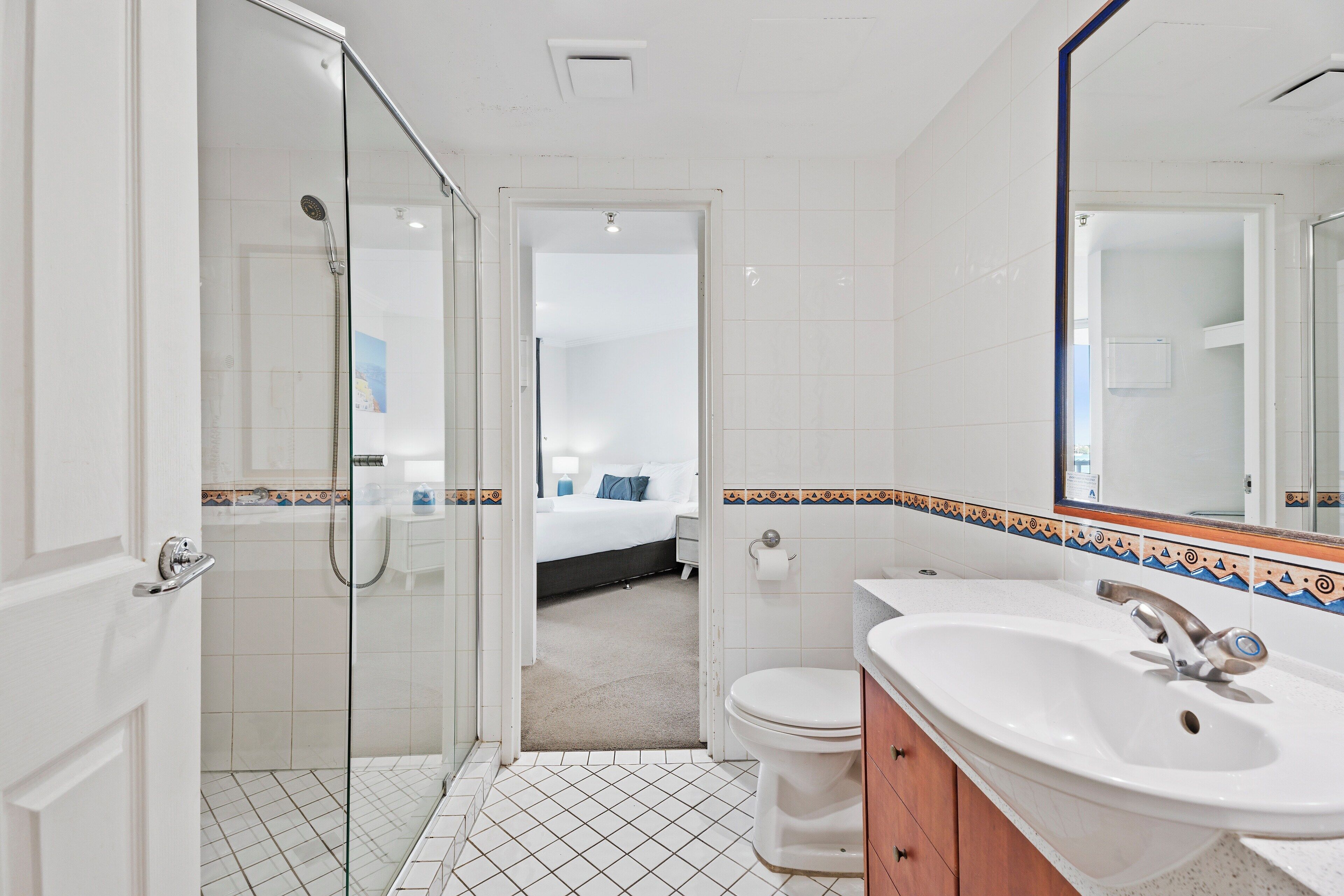 A bathroom with a glass shower enclosure, a white sink, and a toilet.