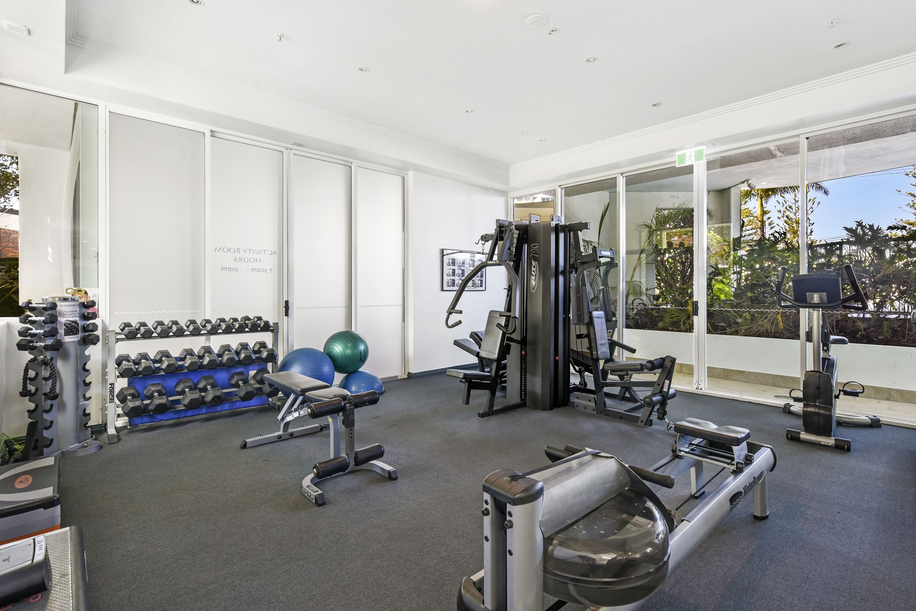 Un gimnasio con diverso equipo de ejercicio, como mancuernas, balones medicinales y máquinas de pesas.