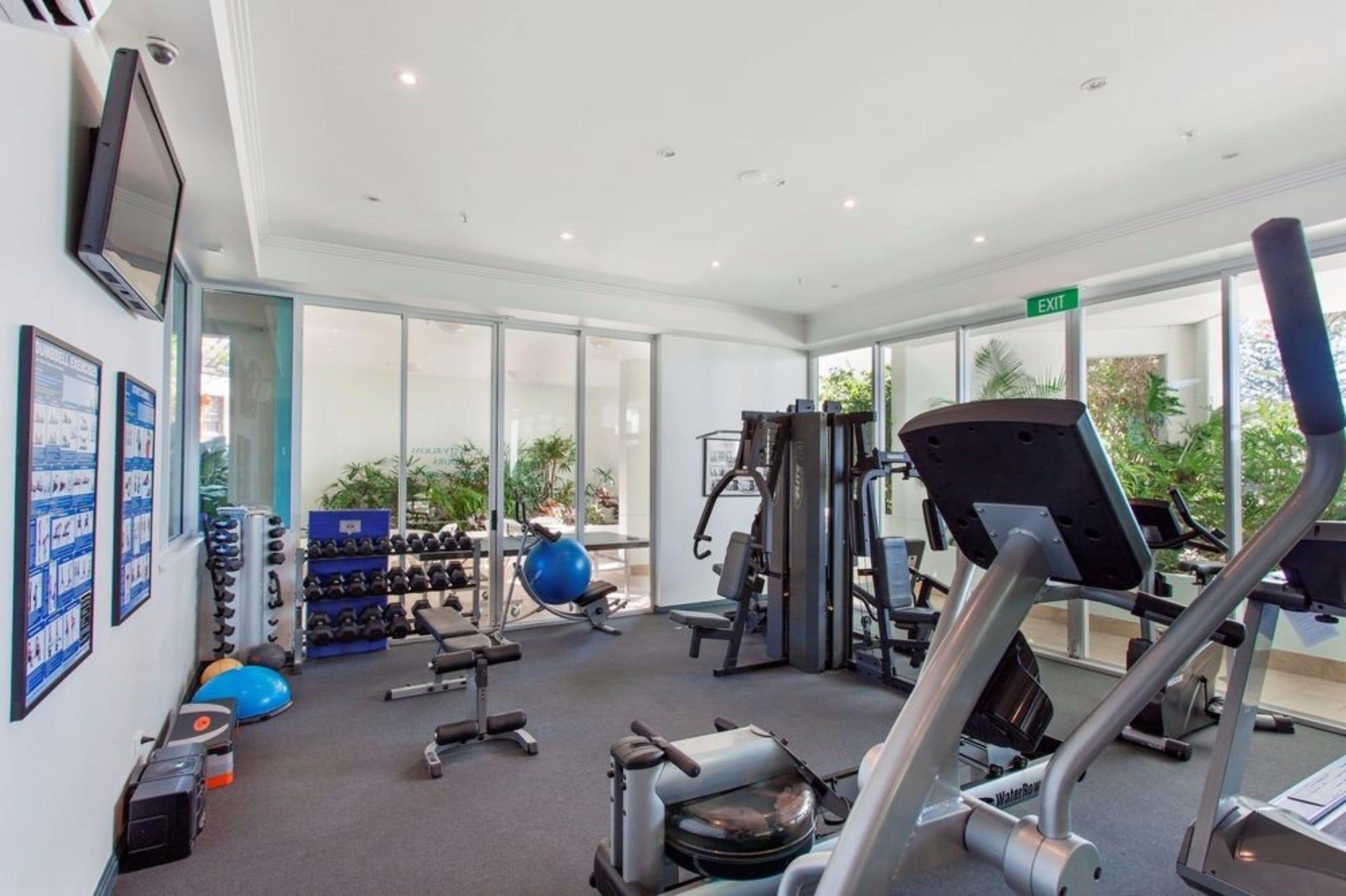 Un gimnasio con equipamiento de ejercicio, una pelota de agua y una cinta de correr.