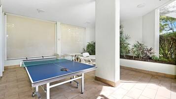 Una mesa de ping pong en una habitación luminosa e inundada de luz, con vistas al verdor exterior.