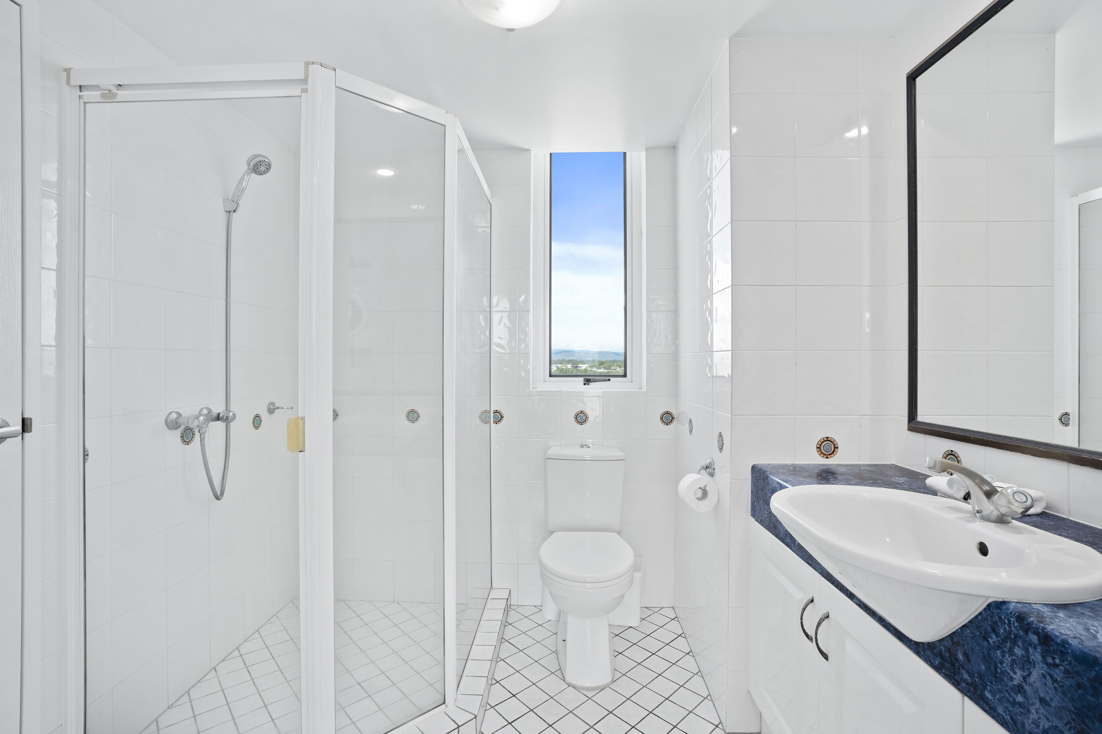 Een moderne badkamer met een douchecabine van glas, een wit toilet en een wastafel met een blauw marmeren aanrechtblad.
