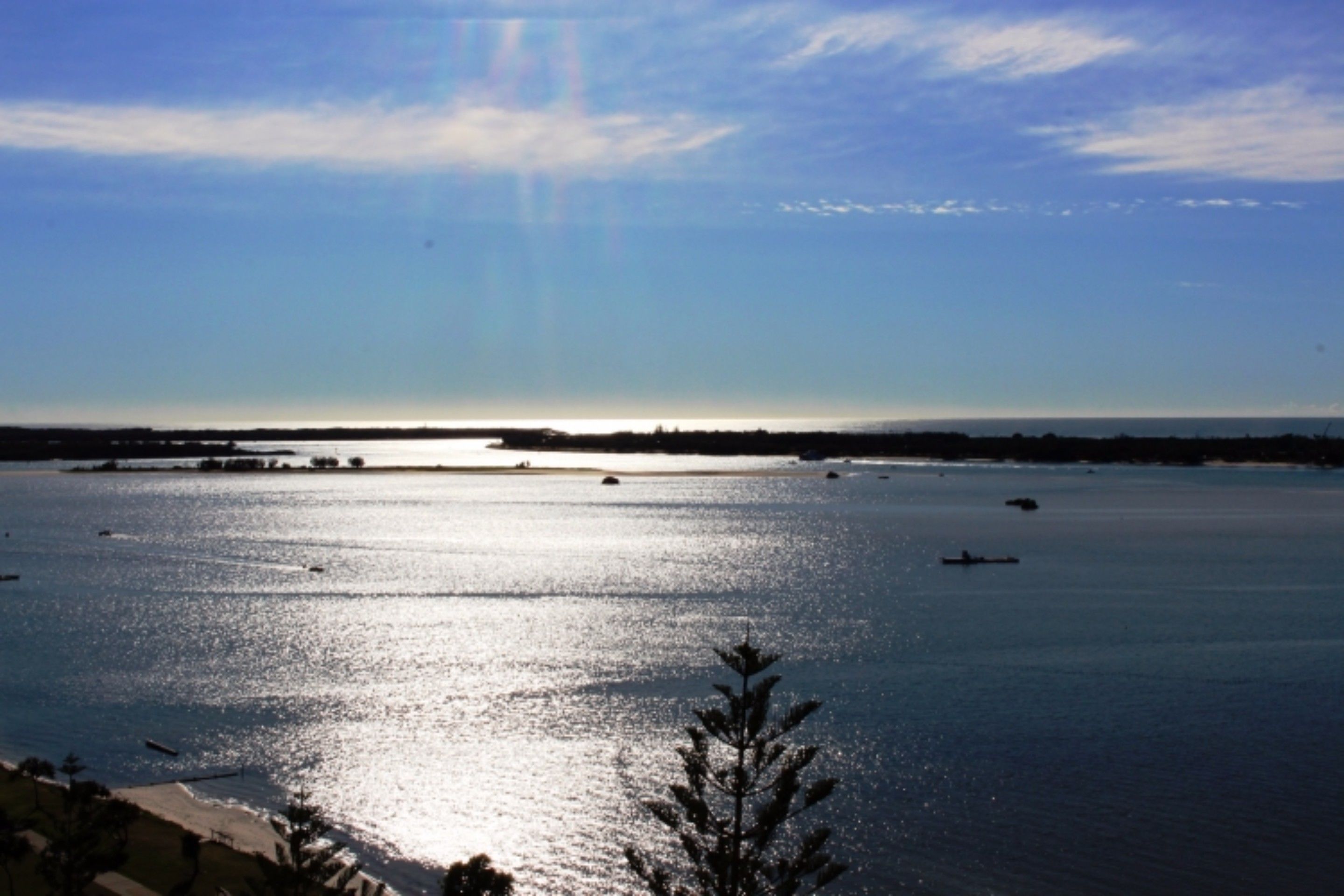 A coastal view with calm water, boats, and a clear sky.