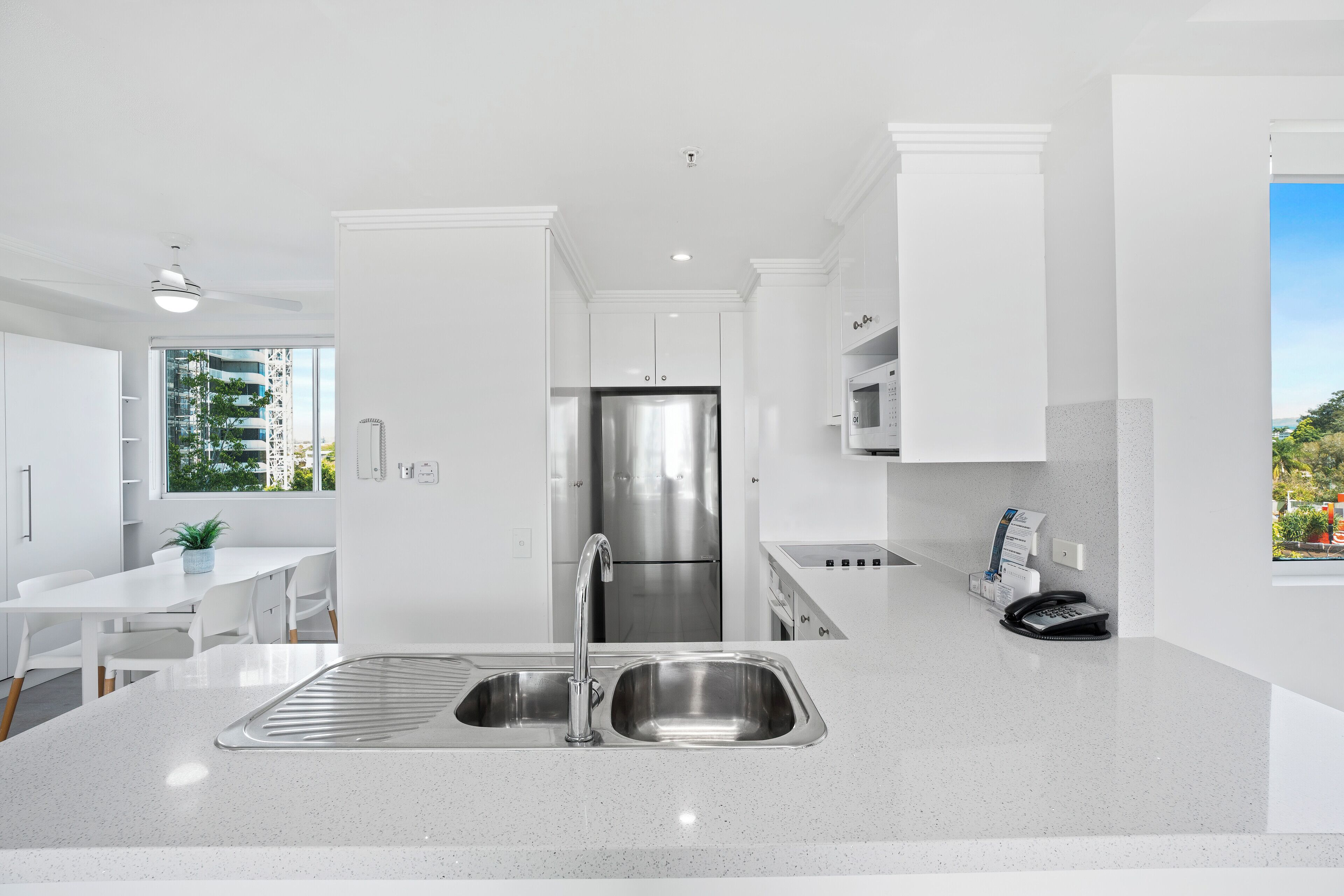 Een moderne keuken met een roestvrijstalen koelkast, een dubbele spoelbak en witte keukenkastjes.