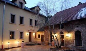 A courtyard with stone buildings, a stone archway, and a small fountain. - Hotel Figo (Bad Kreuznach)