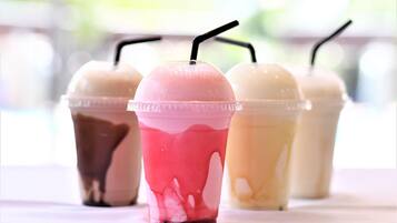 Four cups of iced beverages with straws, placed on a table.