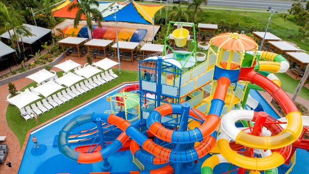 A water park with multiple slides and pools, surrounded by lounge chairs and umbrellas.