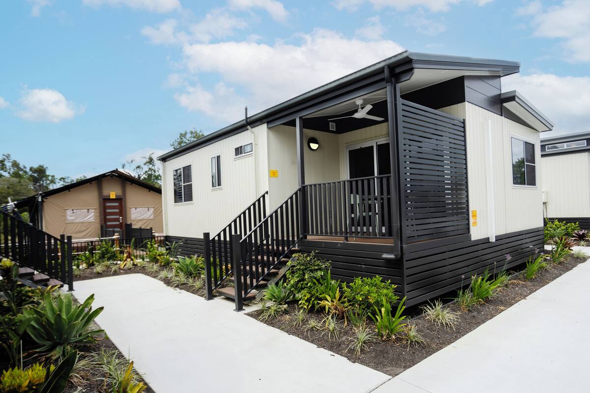 A modern mobile home with a balcony, a porch, and a small garden area.